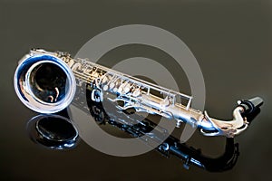 Saxophone tenor. Woodwind Classical Instrument. Jazz, blues, classics. Music. Saxophone on a black background. Black mirror surfac