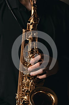 Saxophonist with a beautiful wind musical instrument, musician plays the saxophone, hands close-up, jazz and blues background