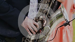 Saxophonist in black suit play jazz on golden saxophone with microphone. Music. Live performance