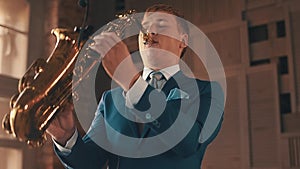 Saxophonist in blue suit play jazz on golden saxophone with microphone. Elegance