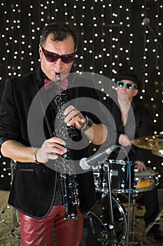 Saxophonist in a bow tie and sunglasses playing photo