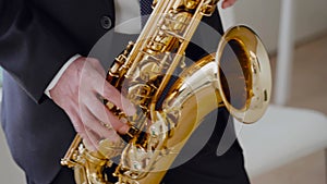 Saxophonist in dinner jacket play on golden saxophone. Live performance. Close-up Jazz music on musical instrument.