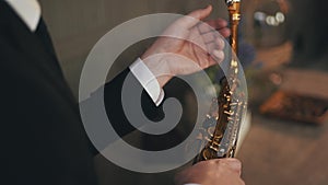 Saxophonist in jacket sitting on chair with golden saxophone. Jazz artist.