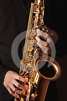 Saxophonist, musician playing the saxophone, hands close-up, wind instrument, music background