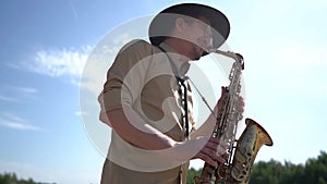 Saxophonist at nature, musician is playing saxophone
