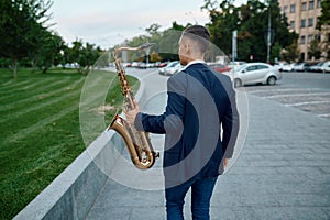 Saxophonist plays melody at the bench in city park