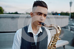 Saxophonist plays melody at the bench in city park