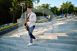 Saxophonist plays the saxophone on stairs in park