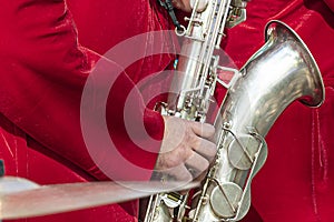 Saxophonist in a red suit close-up. Concept: playing the saxophone, music. Saxophone jazz music instrument Alto sax saxophonist