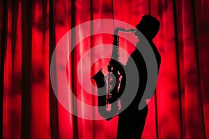 saxophonist silhouette against red curtain