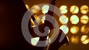 Saxophonist silhouette hands playing musical instrument in spotlights close up.