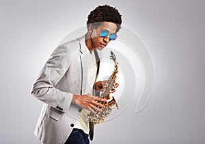 Saxy, and I know it. Studio shot of a fashionable young man playing the saxophone.