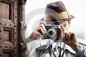 Say cheese. Detective capturing a photo from around the corner while using a retro camera.