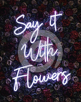 Say it with flow written with neon lights isolated on a heap of colorful flowers