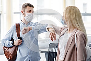 Say hello, social distance and return to work after quarantine. Millennial man and woman in protective masks are touched photo