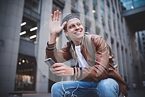 Say hello. Happy man meeting someone. Happy man listening to music with headphones from a smartphone on the street.