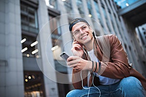 Say hello. Happy man meeting someone. Happy man listening to music with headphones from a smartphone on the street.