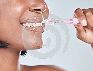 Say hello to a healthy smile. Studio shot of an attractive young woman brushing her teeth against a grey background.