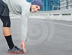 Say limber, stay quick. Portrait of a young male jogger stretchng in the street before a run.