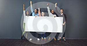 Say it loud, say it proud. Studio shot of a diverse group of people holding a blank placard and cheering against a gray