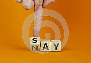 Say nay symbol. Businessman turns a cube, changes the word `say` to `nay`. Beautiful orange background. Copy space. Business,
