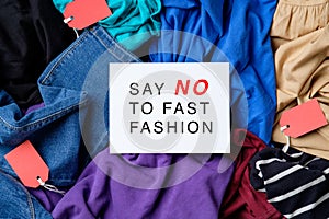 Say No To Fast Fashion sign on paper card over heap of clothes. Fast Fashion is bad for the environment