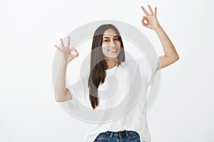 Say okay. Portrait of friendly-looking happy woman in white t-shirt and jeans, raising hands with great or acception