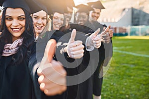 Say yes to the future. Portrait of a group of students showing thumbs up on graduation day.