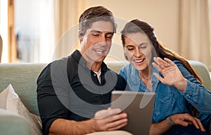 Saying hi to the family abroad. a couple using a digital tablet while relaxing together at home.