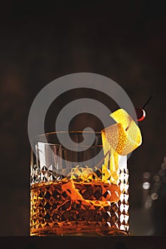 Sazerac, classic alcoholic cocktail with cognac, bourbon, absinthe, bitters, sugar and lemon zest. Old wooden background with copy