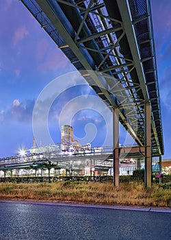 Scaffold with pipeline and Illuminated petrochemical production plant at twilight at Port of Antwerp
