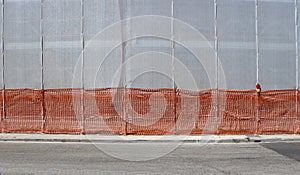 Scaffold plastic sheeting covering a facade under refurbishment, a sidewalk and an asphalt road.