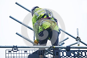 Scaffold worker dismantling access structure on construction building site