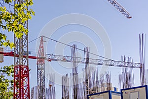 Scaffolding and big industrial tower cranes with unfinished high raised buildings on a blue sky in background. Modern civil