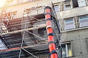 Scaffolding with big red plastic slide chute for rubble debris removal on old historica building facade renewal