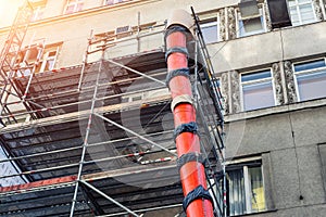 Scaffolding with big red plastic slide chute for rubble debris removal on old historica building facade renewal photo