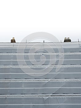 Scaffolding covered with white safety net in a city. House reconstruction work on progress. Construction industry