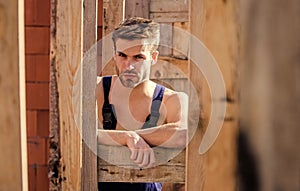 Scaffolding and frameworks. View through scaffoldings. Handsome builder at construction site. Guy works at construction