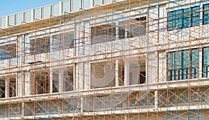 Scaffolding of house building. Lattice mast, cables or poles in busy industrial under construction site with cranes. Steel or