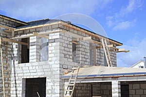 scaffolding and house under construction with grey folding roof on waterproofing layer