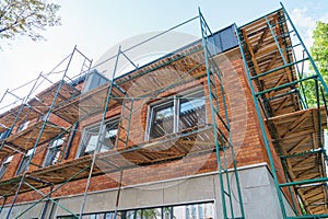Scaffolding is installed along the wall of the building under construction. Plastering and painting of the facade of the house.