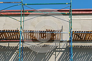 Scaffolding is installed along the wall of the building under construction. Plastering and painting of the facade of the house.