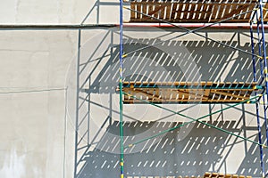 Scaffolding is installed along the wall of the building under construction. Plastering and painting of the facade of the house.