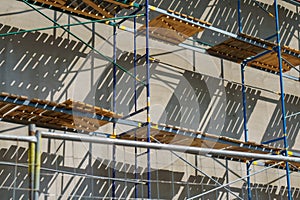 Scaffolding is installed along the wall of the building under construction. Plastering and painting of the facade of the house.