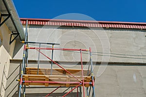 Scaffolding is installed along the wall of the building under construction. Plastering and painting of the facade of the house.