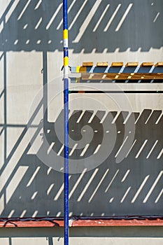 Scaffolding is installed along the wall of the building under construction. Plastering and painting of the facade of the house.