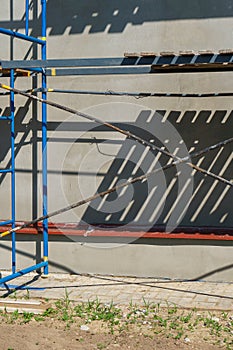 Scaffolding is installed along the wall of the building under construction. Plastering and painting of the facade of the house.