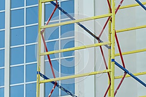 Scaffolding is installed along the wall of the building under construction. Plastering and painting of the facade of the house.