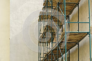 Scaffolding is installed along the wall of the building under construction. Plastering and painting of the facade of the house.