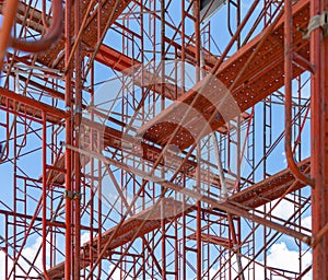 Scaffolding. Lattice mast, cables or poles in busy industrial under construction site with cranes. Steel or metal structure.